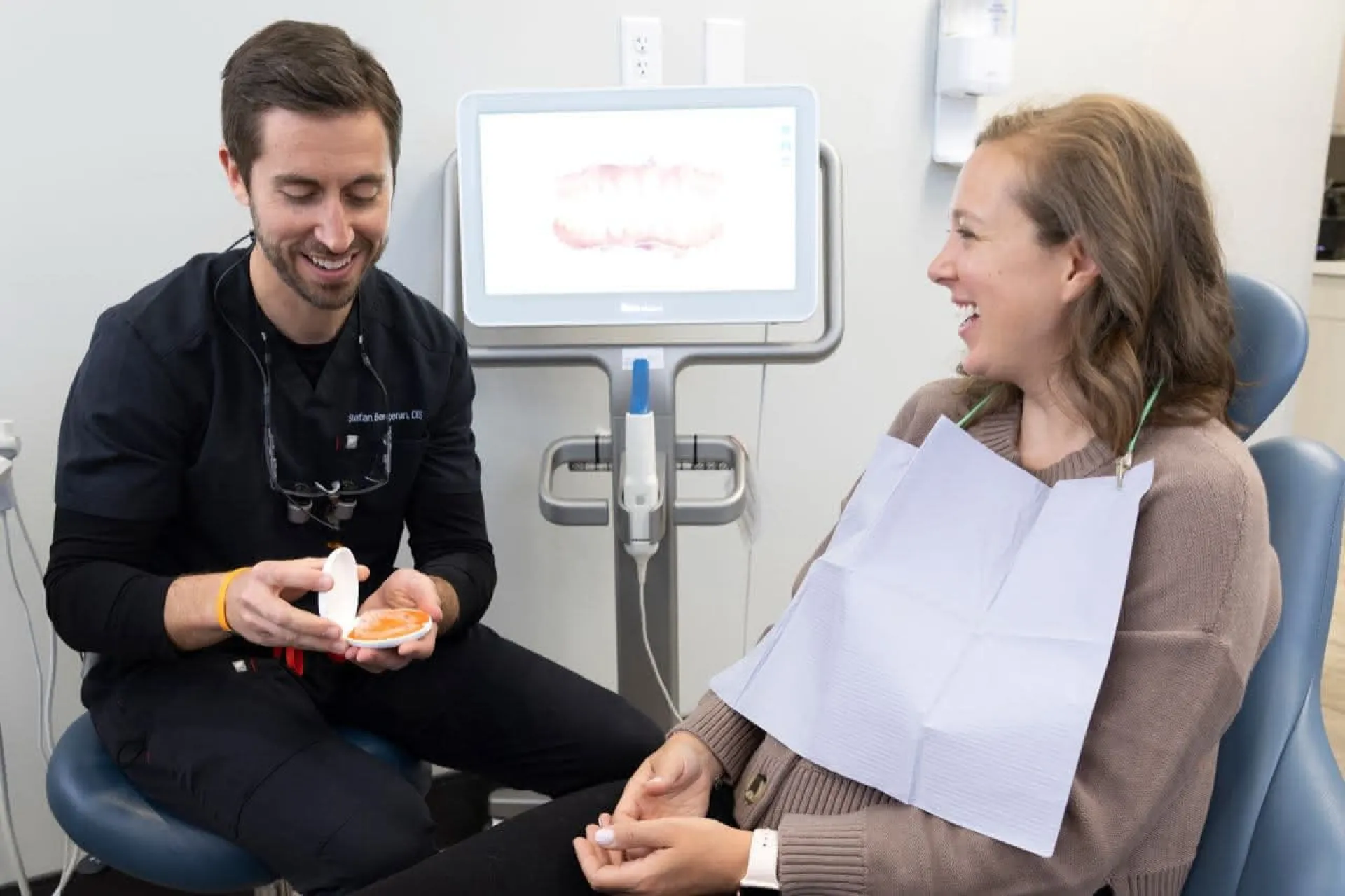 A dentist holding a mirror in front of a patient in a dental chair