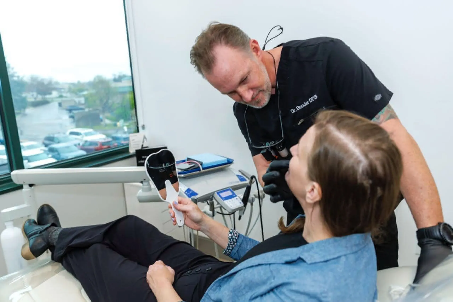 Dr. Bender examining a patient holding a hand mirror
