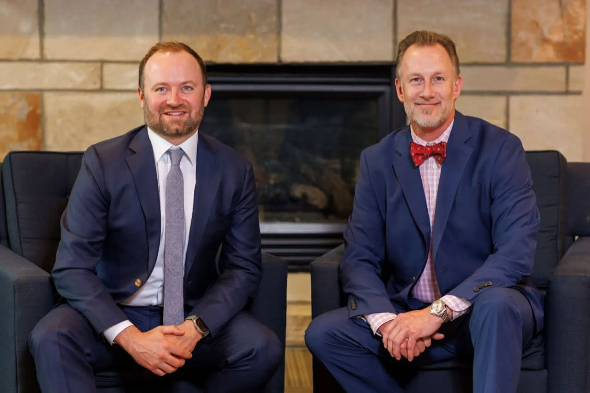 Two doctors in suits in front of a fireplace