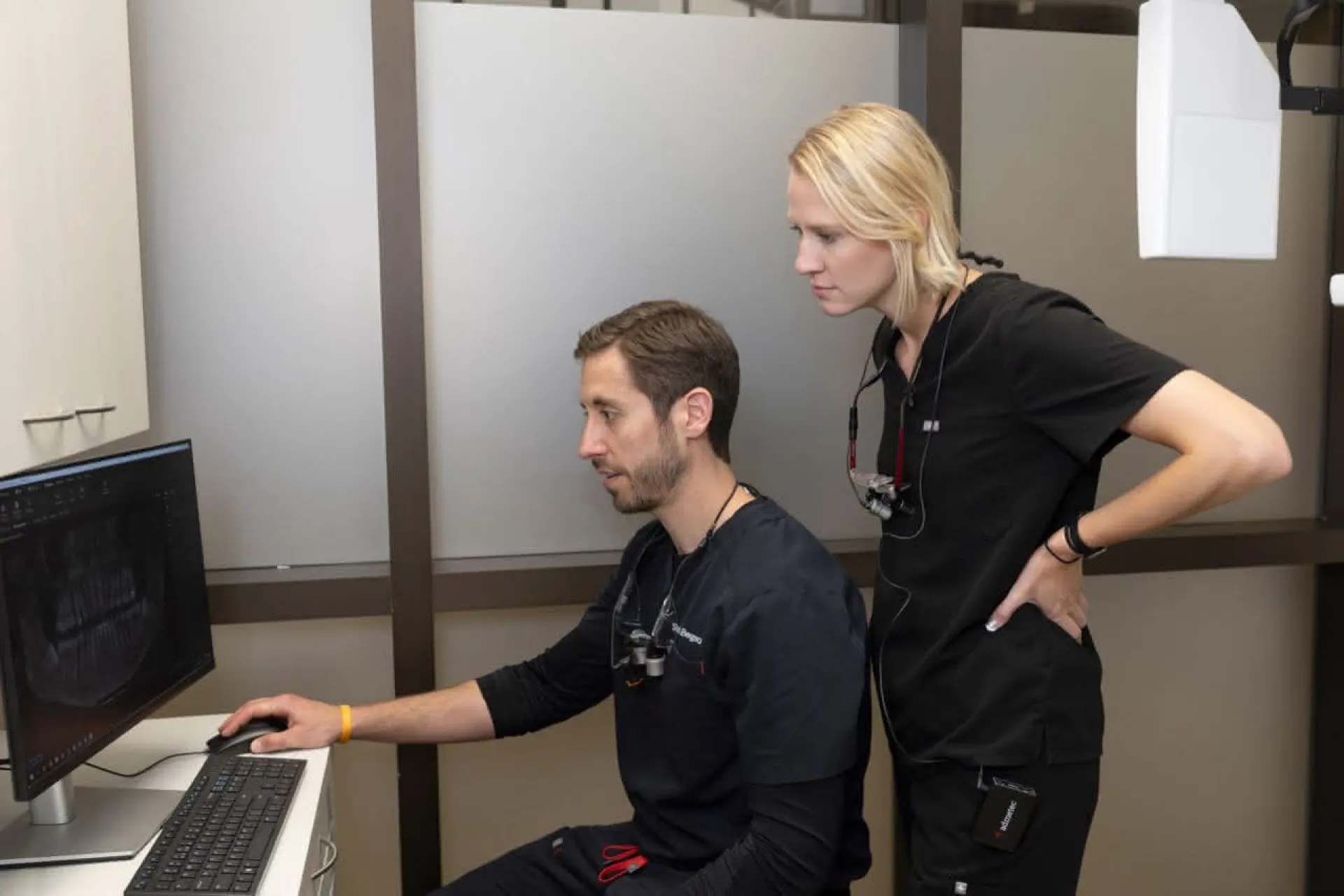 Staff stands behind doctor at computer reviewing patients X-ray