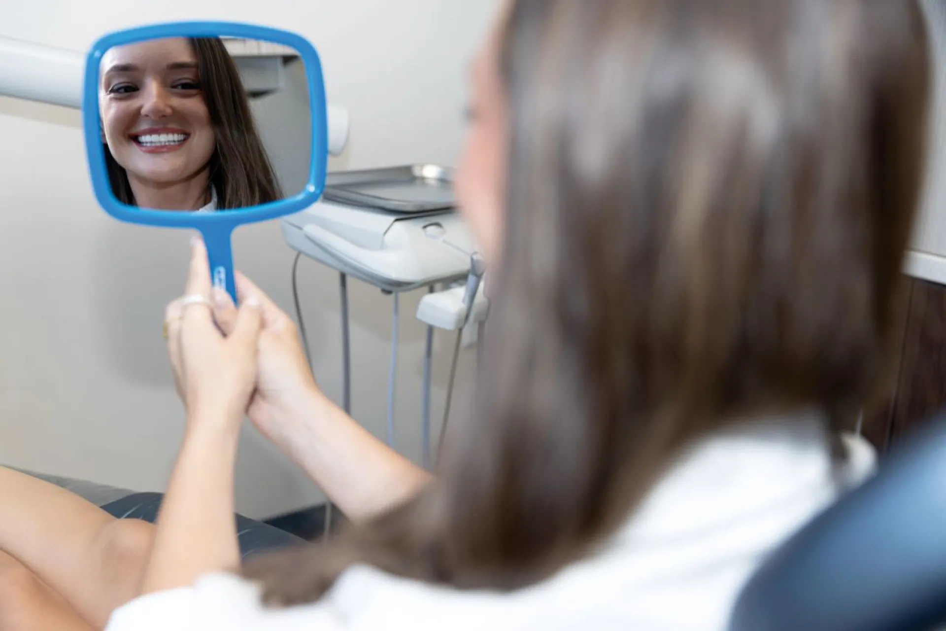 Patient holding blue mirror smiling
