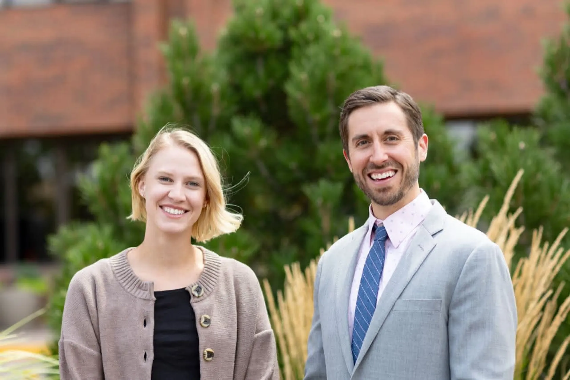 Two doctors standing in front of prairie grass smiling