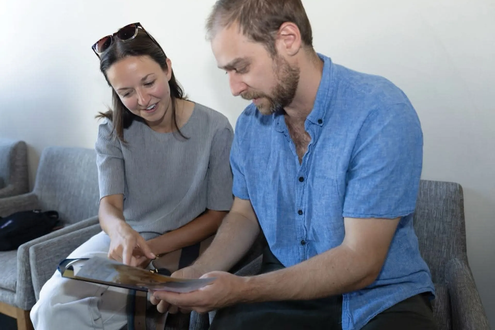 Two people sitting on grey chairs filling out forms