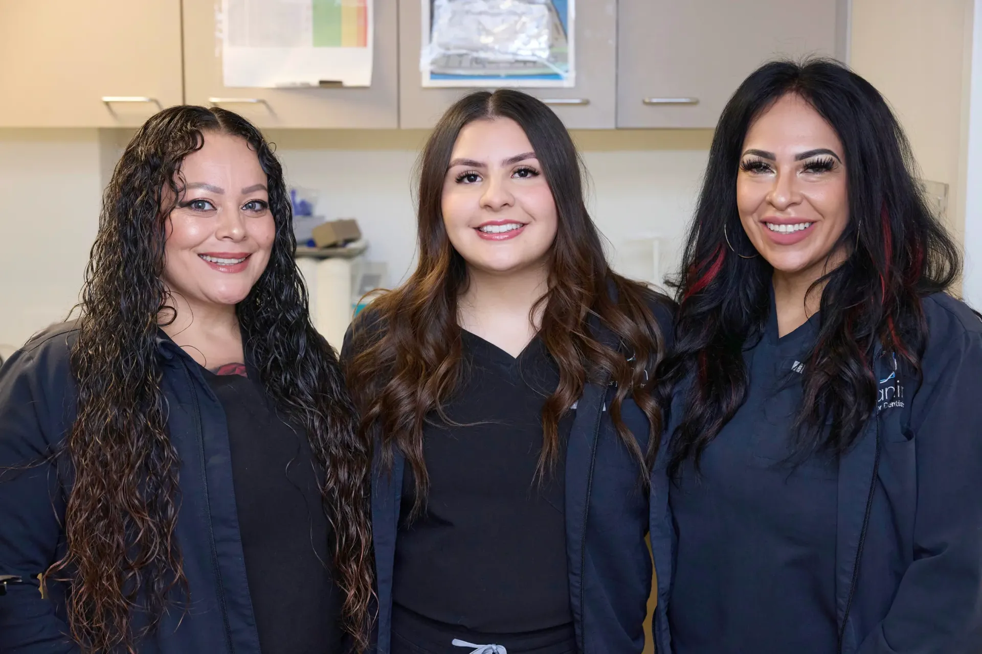 Three team members in front of a cabinet