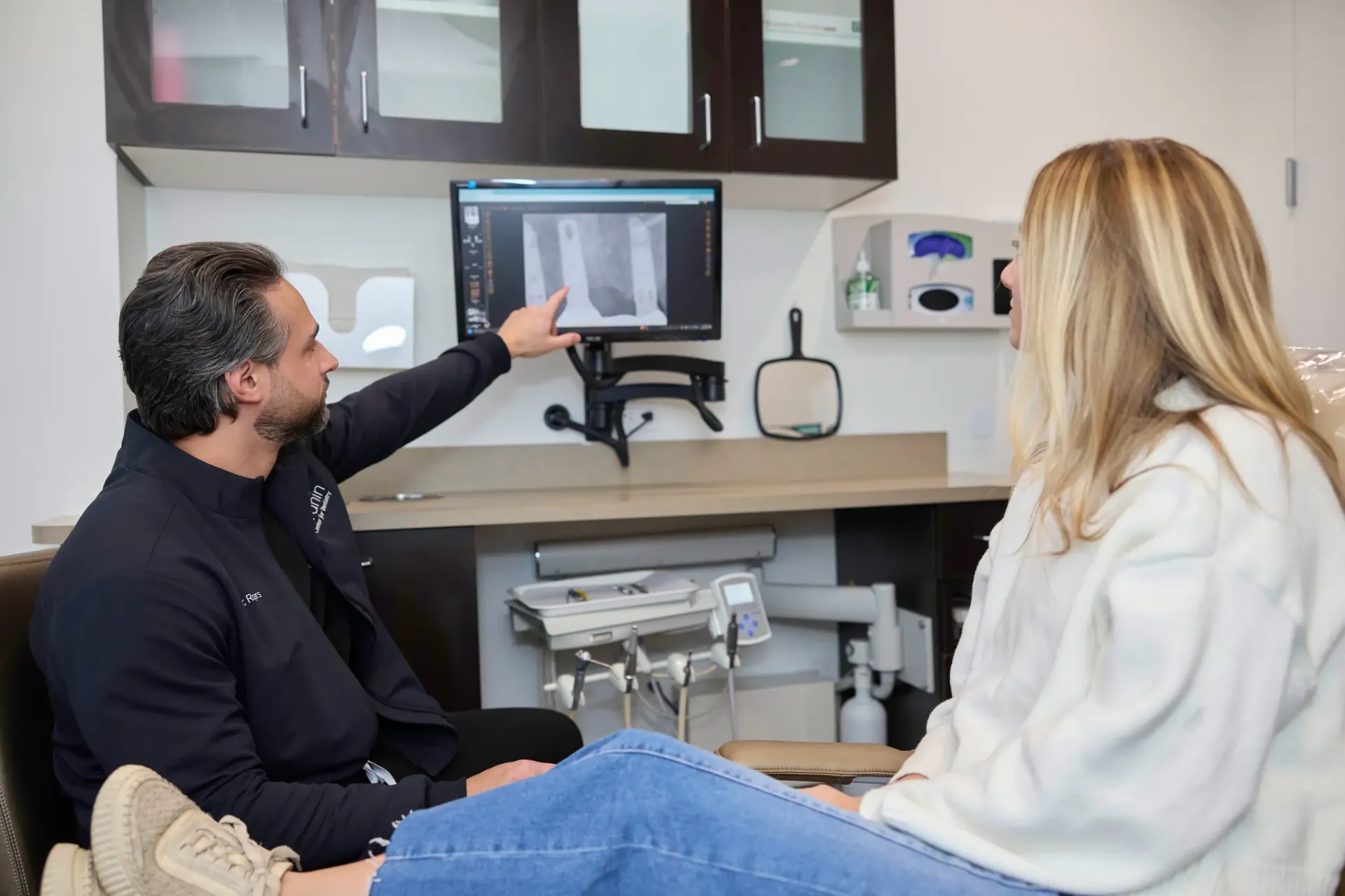 A doctor pointing at an x-ray on a monitor
