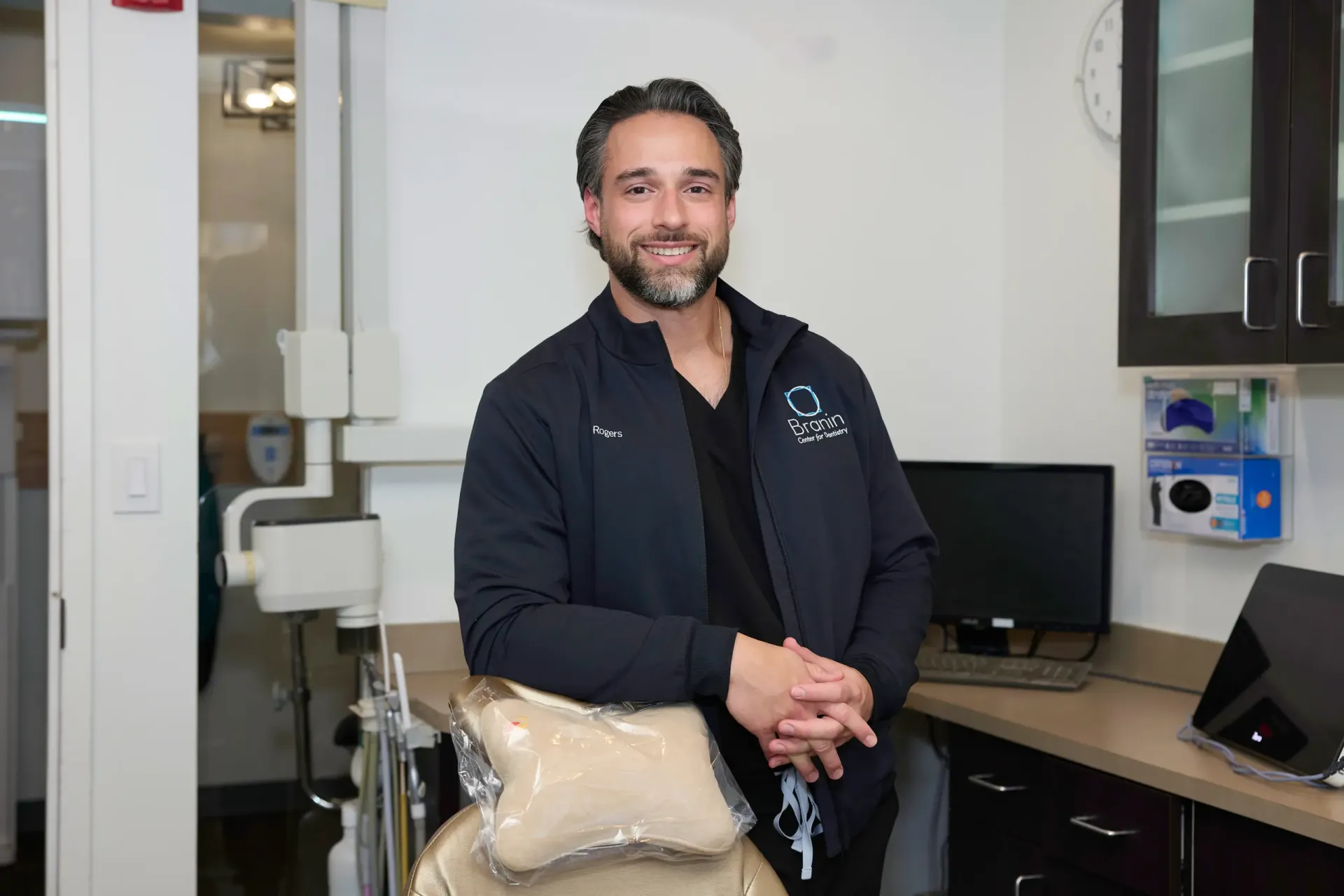 Dr. Rogers leaning on a tan dentist chair