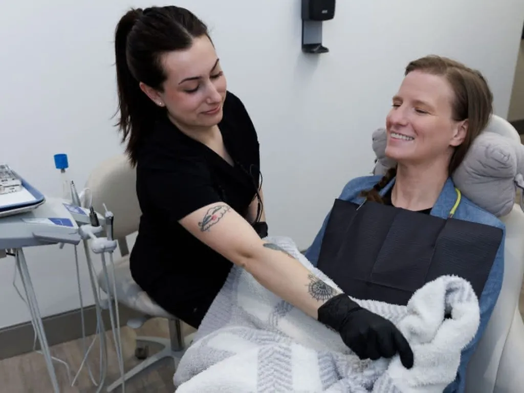 Staff member adjusting a blanket on a patient