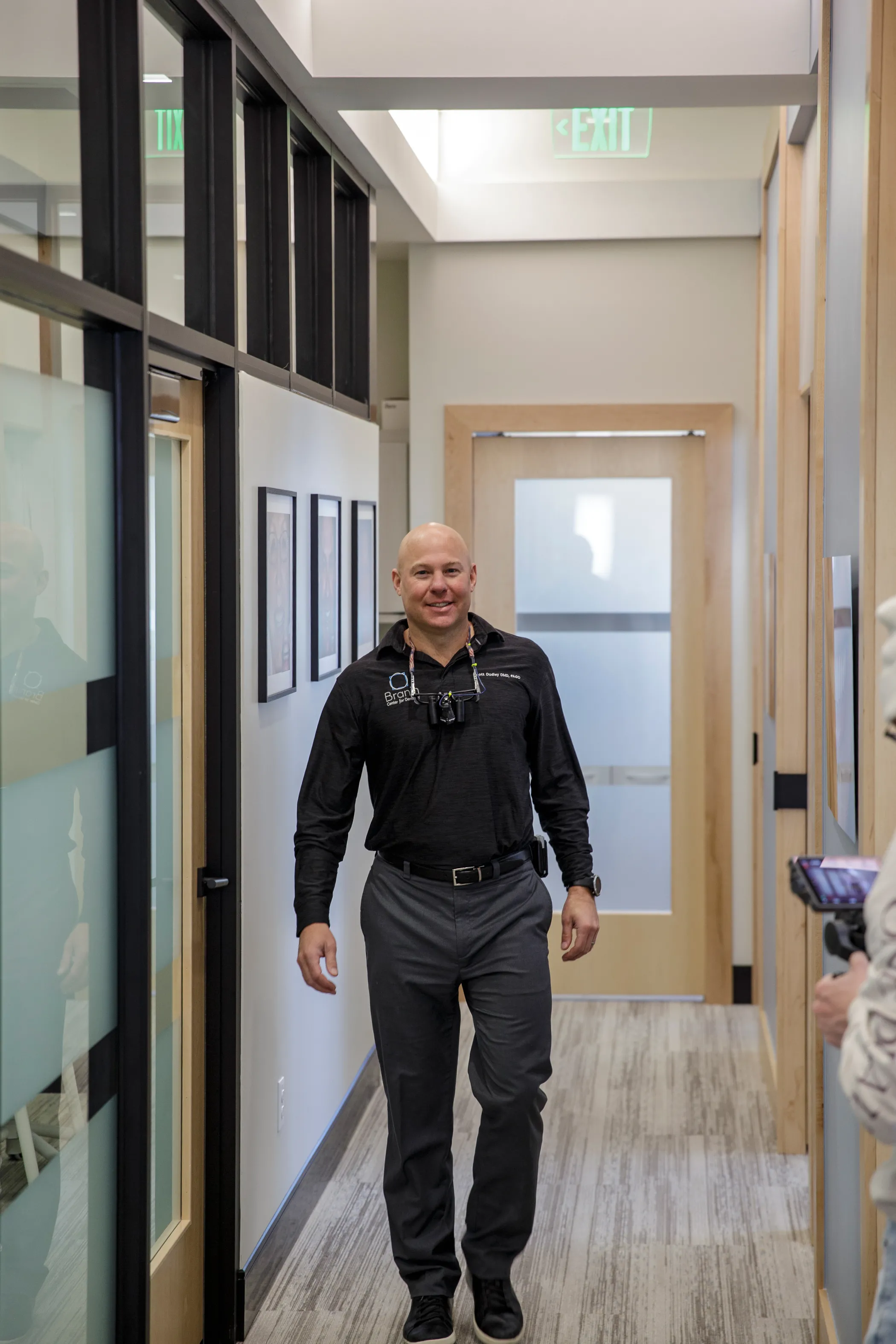 Dr. Dudley smiling as he walks down office hallway.