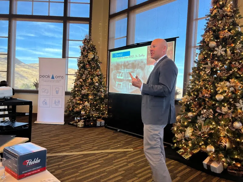 Scott Dudley lecturing in front of holiday trees